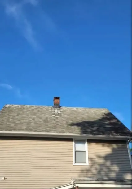 House with a worn, stained pitched roof before replacement