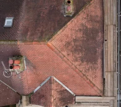 Overhead view of a weathered hip roof before replacement
